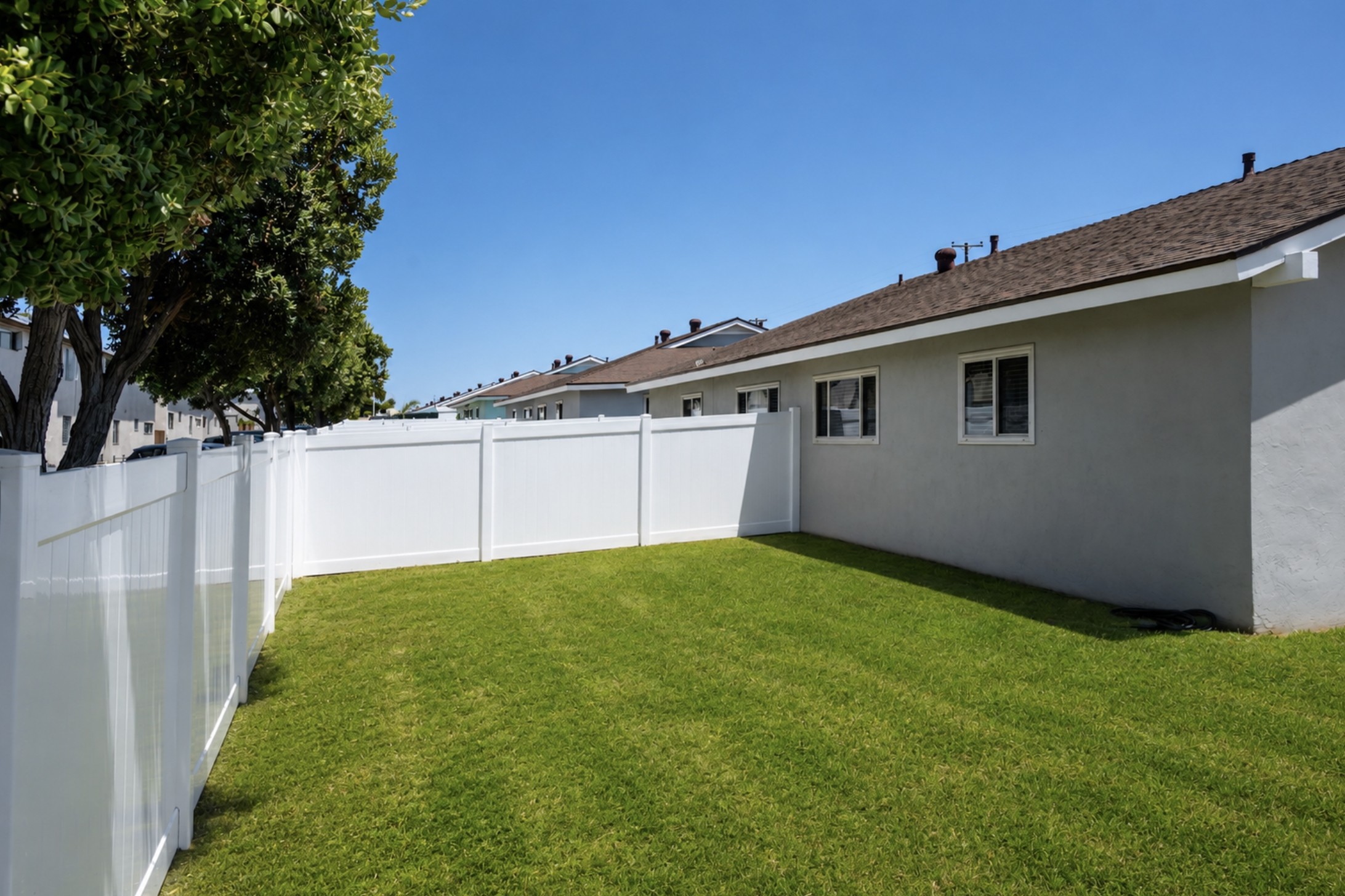 Gallery Fenced backyard with grassy lawn alongside a coastal bungalow rental residence.