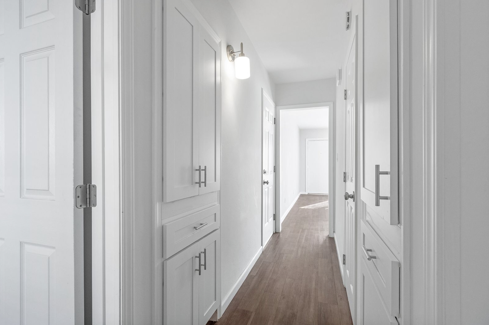 Gallery Bright hallway with white doors, built-in storage, and access to the renovated bathroom.