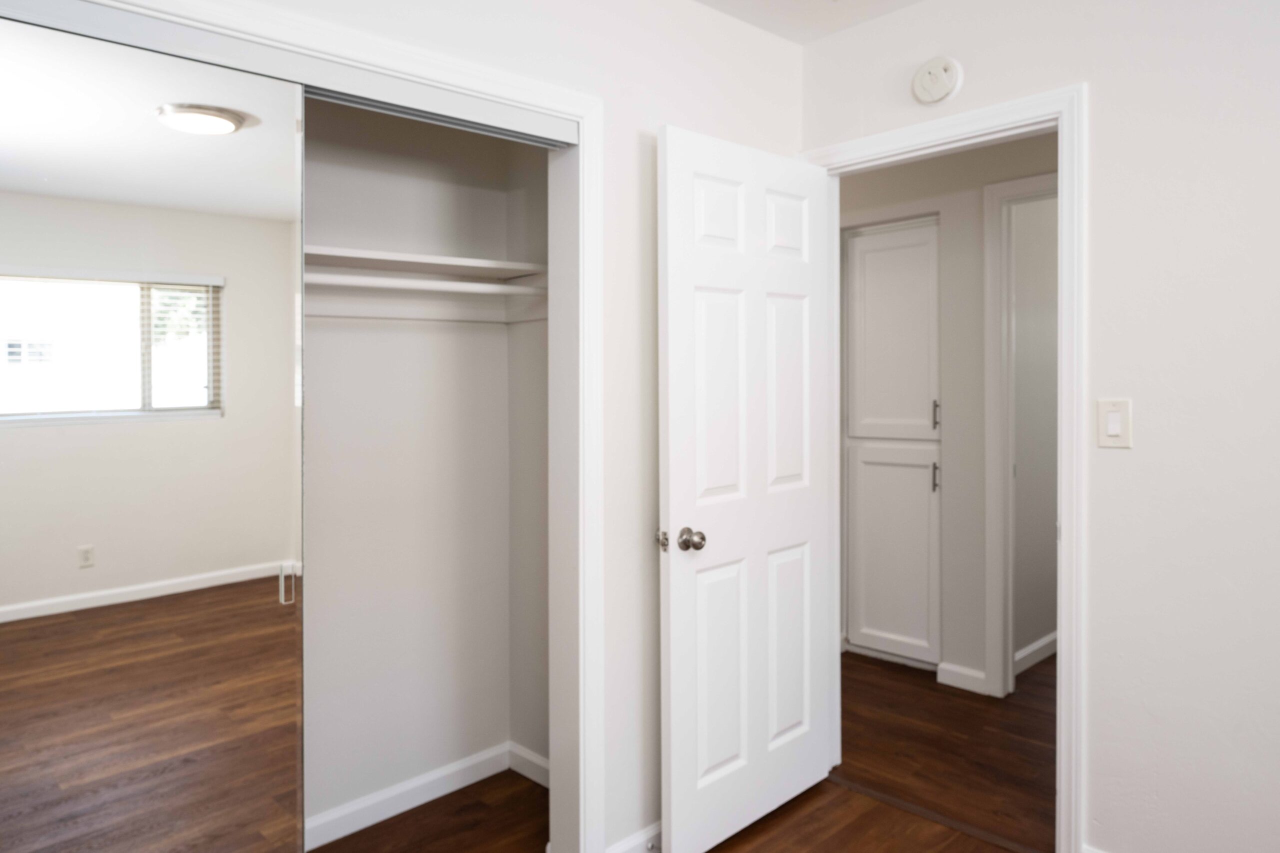 Gallery Bedroom with mirrored wardrobe doors, spacious closet, and wood-look flooring.
