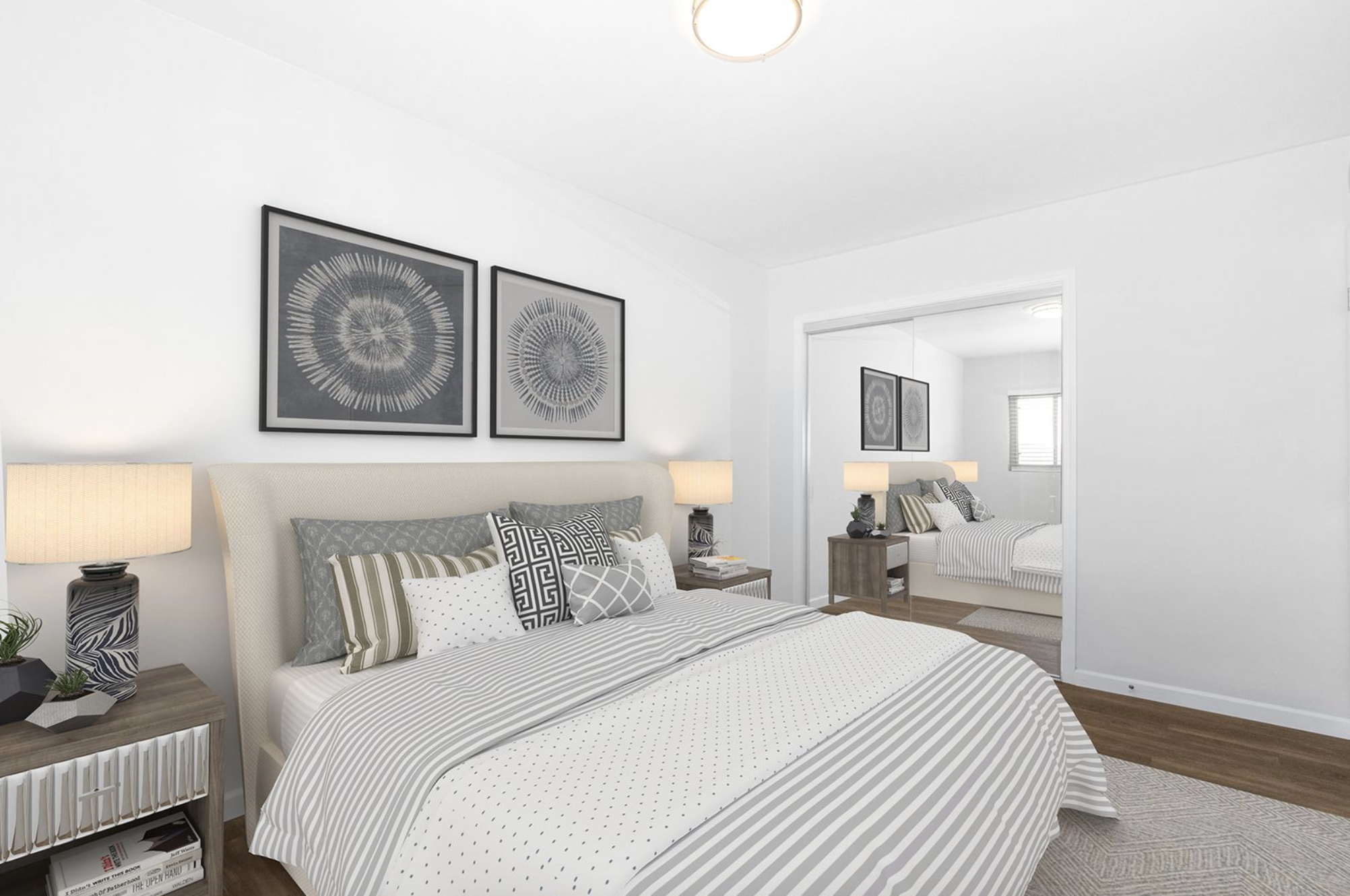Gallery Furnished bedroom with wood-look flooring, mirrored wardrobe doors, and bedside tables.