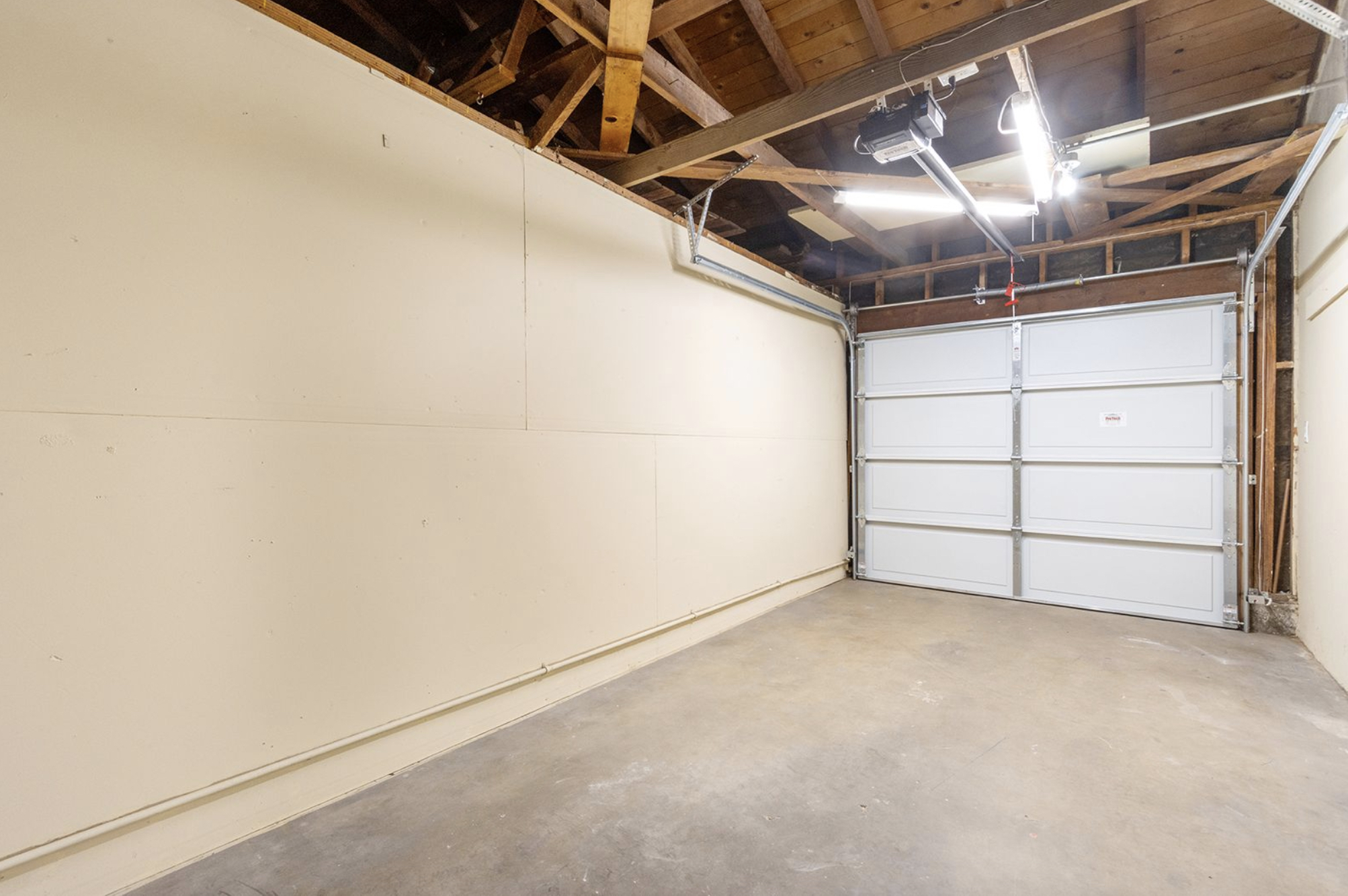 Gallery Interior of private residential garage with concrete floor and overhead garage door.