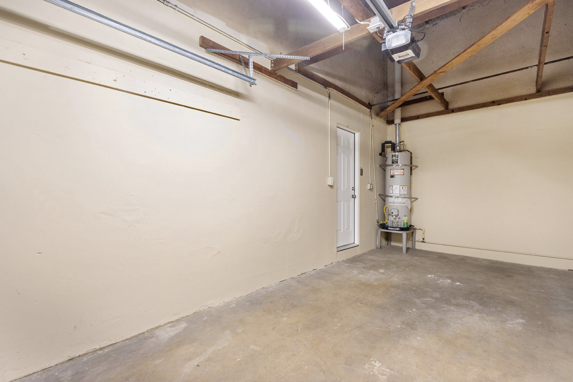 Gallery Residential garage interior with concrete flooring, exposed ceiling beams, and utility equipment.