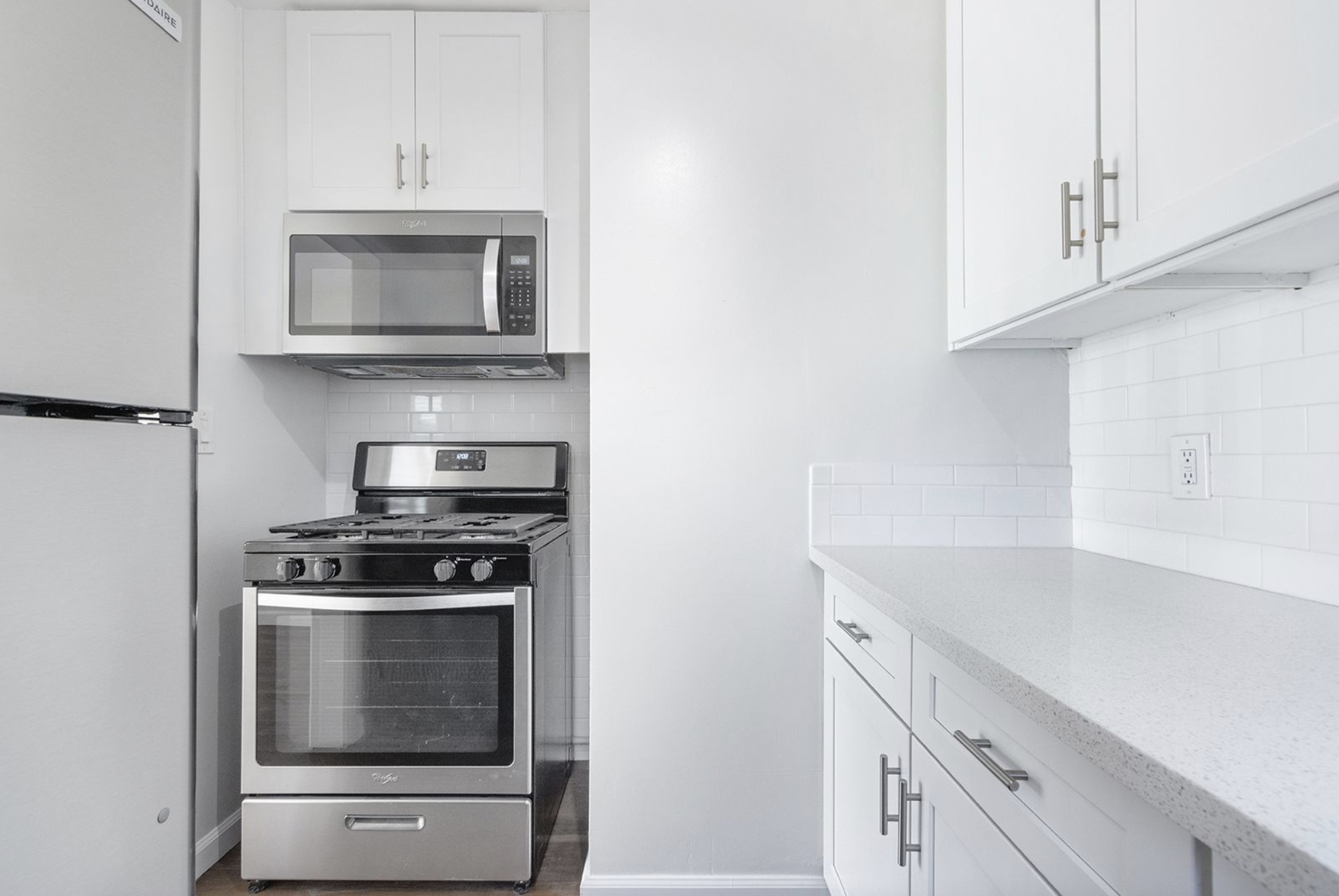 Gallery Stainless steel gas range, microwave, and white cabinetry in renovated kitchen.