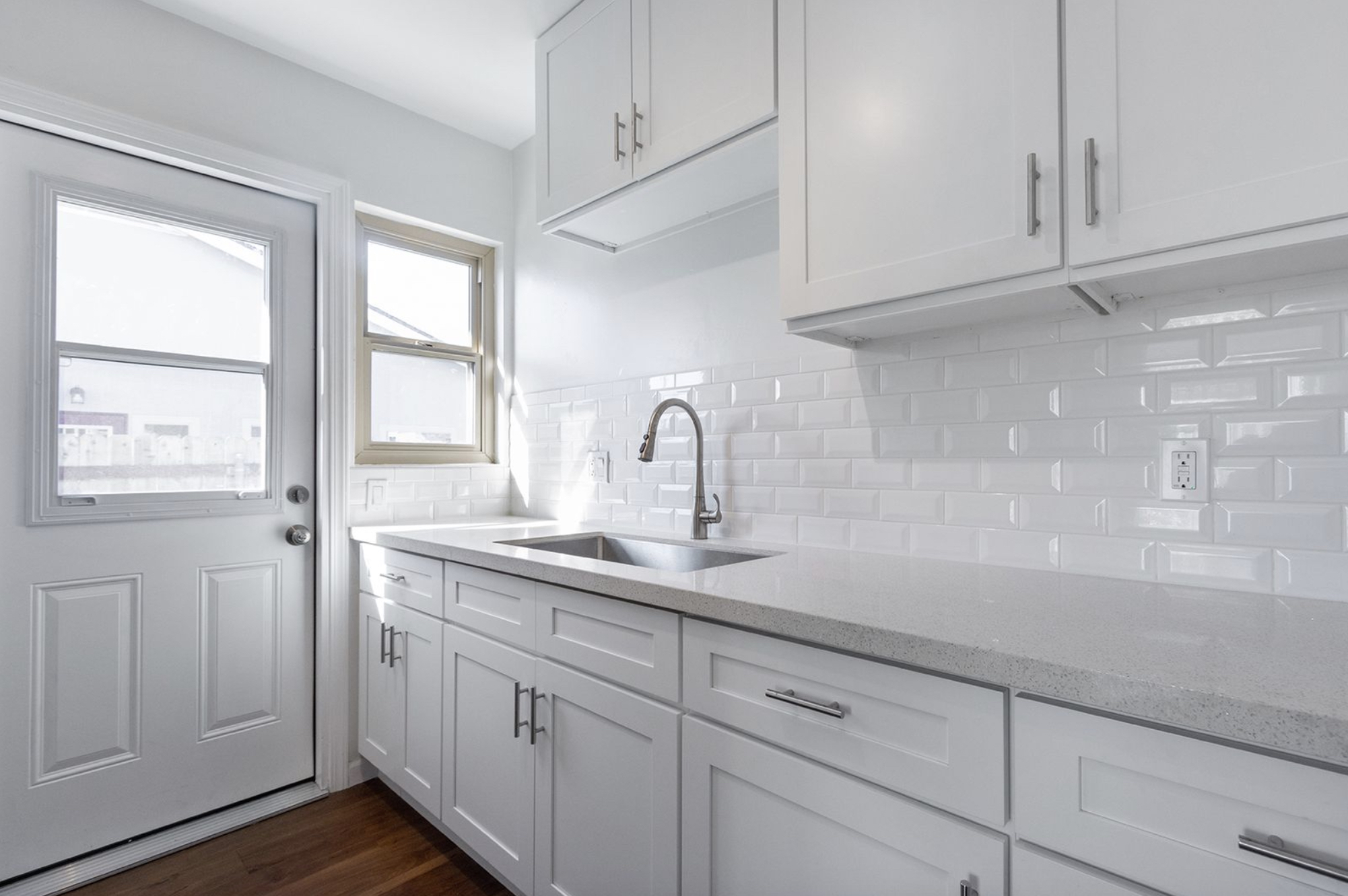 Gallery Bright renovated kitchen with Shaker-style cabinetry, stainless steel sink, and countertop workspace.