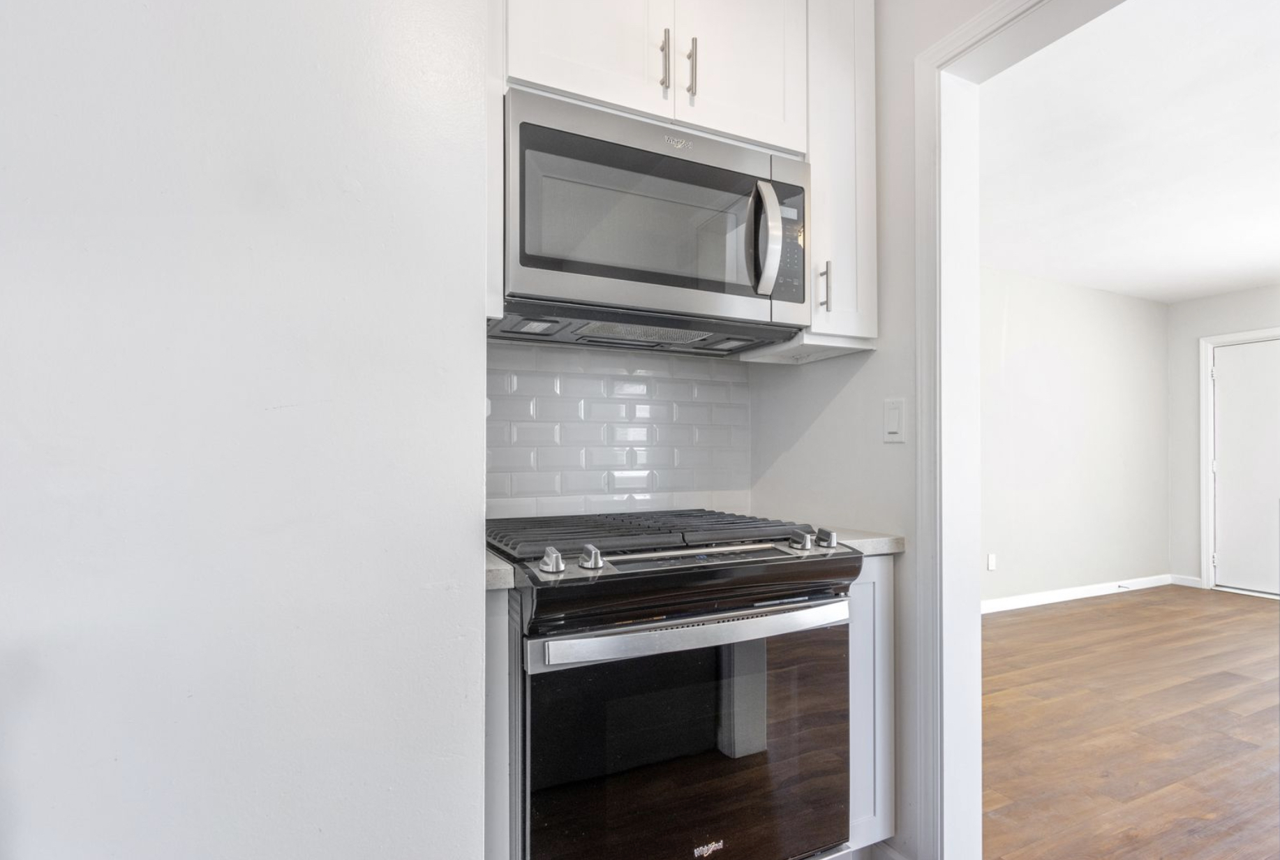 Gallery Stainless steel gas range and microwave in renovated coastal bungalow kitchen.