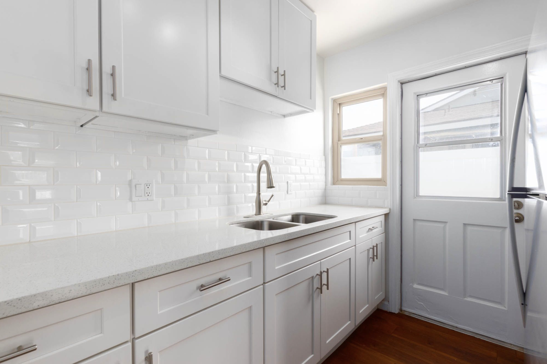Gallery Renovated kitchen with white Shaker-style cabinets, quartz countertops, and stainless steel sink.